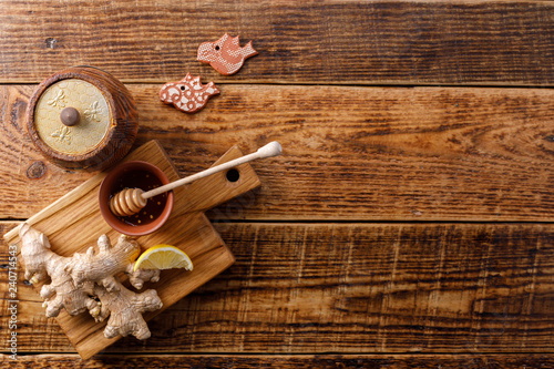 Barrel of honey with ginger root and lemon on wooden background. Flat lay. Copy space.
