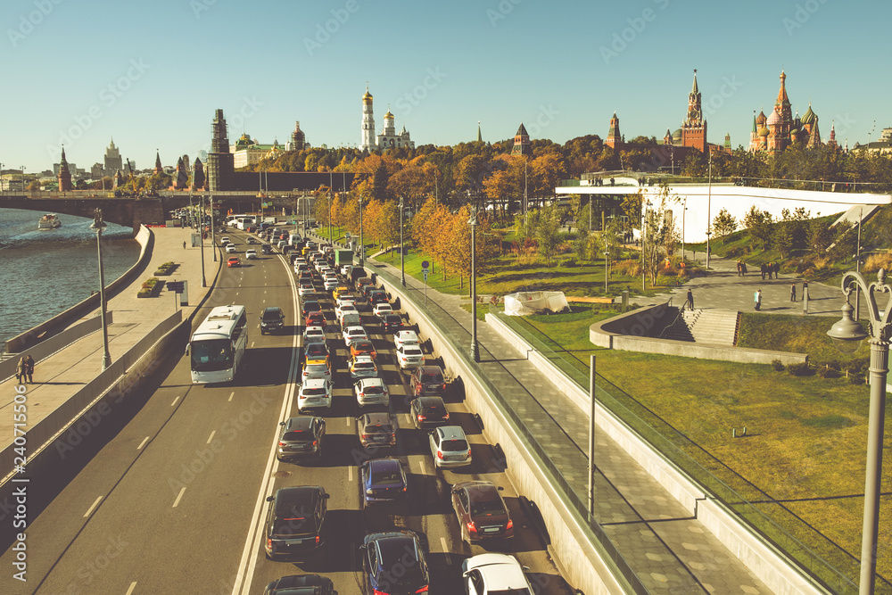 Obraz premium Aerial view from Moscow River on embankment with urban transport road and footpath. Moscow Kremlin and St Basil's Cathedral on background. Famous landmarks.