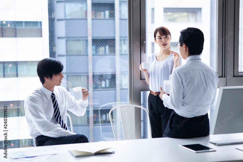デスクに腰かけ休憩するオフィスシーン デスクに腰かけ休憩するオフィスシーン