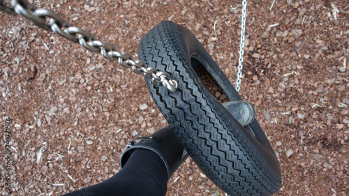 Playing in a playground, foot swinging across a tyre chain bridge with wood chips below photo