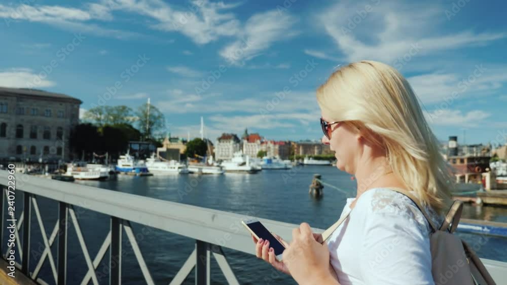 Woman talking on the phone on the go. Walking over the bridge in the background of the Stockholm city line in Sweden Woman talking on the phone on the go. Walking over the bridge in the background of the Stockholm city line in Sweden