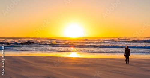 Silhouette girl watching a sunset on a sandy beach