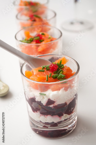 closeup of beet and salmon appetizers in little glasses on white background