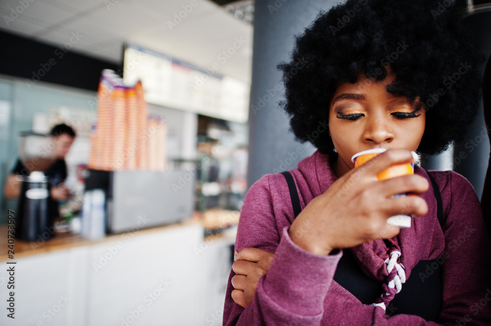 Curly hair african american woman wear on sweater posed at cafe indoor with cup of tea or coffee. Curly hair african american woman wear on sweater posed at cafe indoor with cup of tea or coffee.