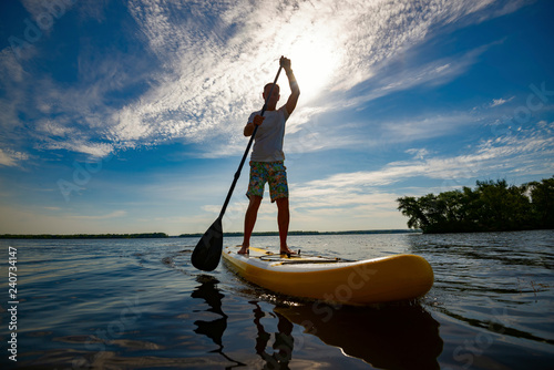 Happy man is paddling on a SUP board