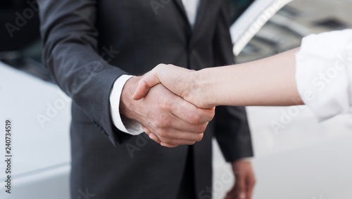Female salesman shaking hands with customer in dealership photo