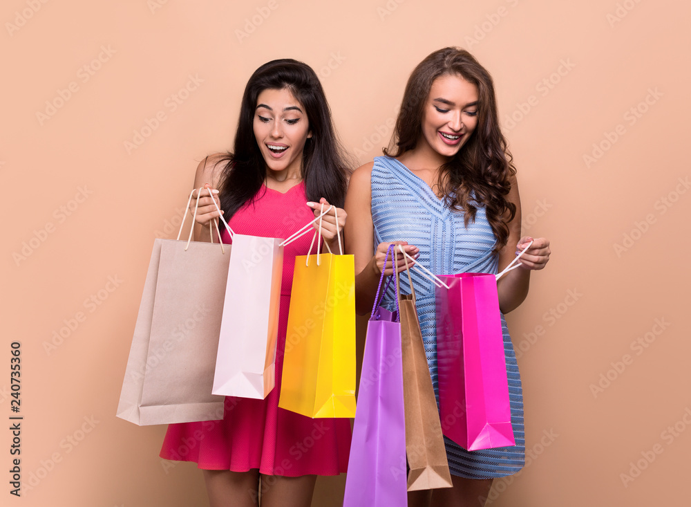 Happy excited women looking into shopping bags Happy excited women looking into shopping bags