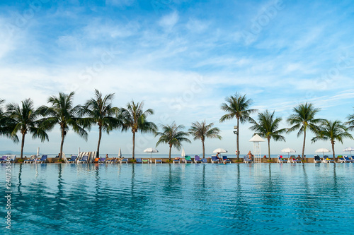 People has relax between the swimming pool and the tropical sea at the morning time.