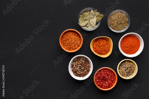 Colourful spices in bowls on black background