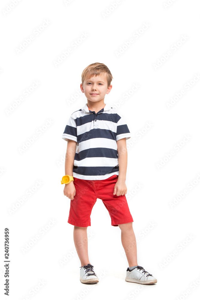 Full length portrait of cute little kid boy in stylish clothes looking at camera and smiling, standing against white studio wall. Kids fashion concept Full length portrait of cute little kid boy in stylish clothes looking at camera and smiling, standing against white studio wall. Kids fashion concept