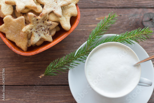 cappuccino and homemade cookies on wooden background with spruce twig