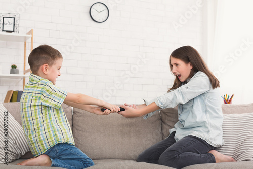 Brother and sister fighting over remote control at home photo