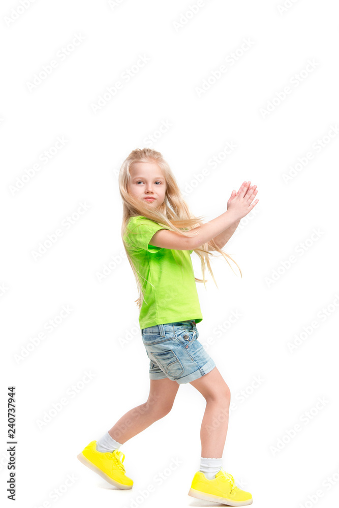 Full length portrait of cute little kid girl in stylish jeans clothes looking at camera and smiling, standing against white studio wall. Kids fashion concept Full length portrait of cute little kid girl in stylish jeans clothes looking at camera and smiling, standing against white studio wall. Kids fashion concept