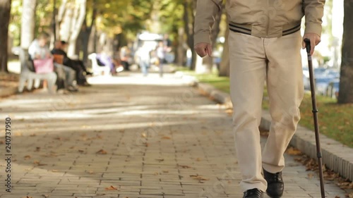 Ill aged man walking in park early warm autumn limping slowly, good weather photo