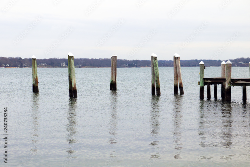 Coastal harbor with wooden pier dock on sandy rocky beach Coastal harbor with wooden pier dock on sandy rocky beach