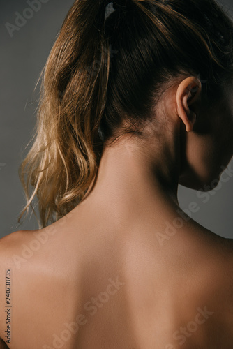 back view of blonde woman with ponytail on grey background
