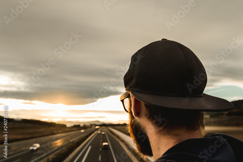 Guy looking at a sunset .Portrait of a modern guy with cap and sunglasses . Concept of freedom and inspiration