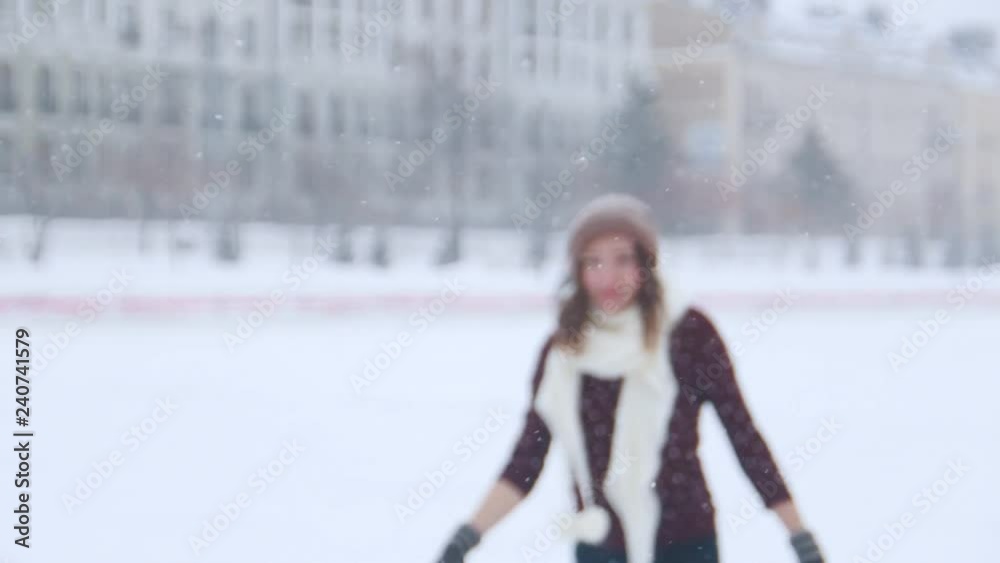 A young woman ice skating outside. Sees her friend, waving to them with a hand, skate closer to the camera A young woman ice skating outside. Sees her friend, waving to them with a hand, skate closer to the camera