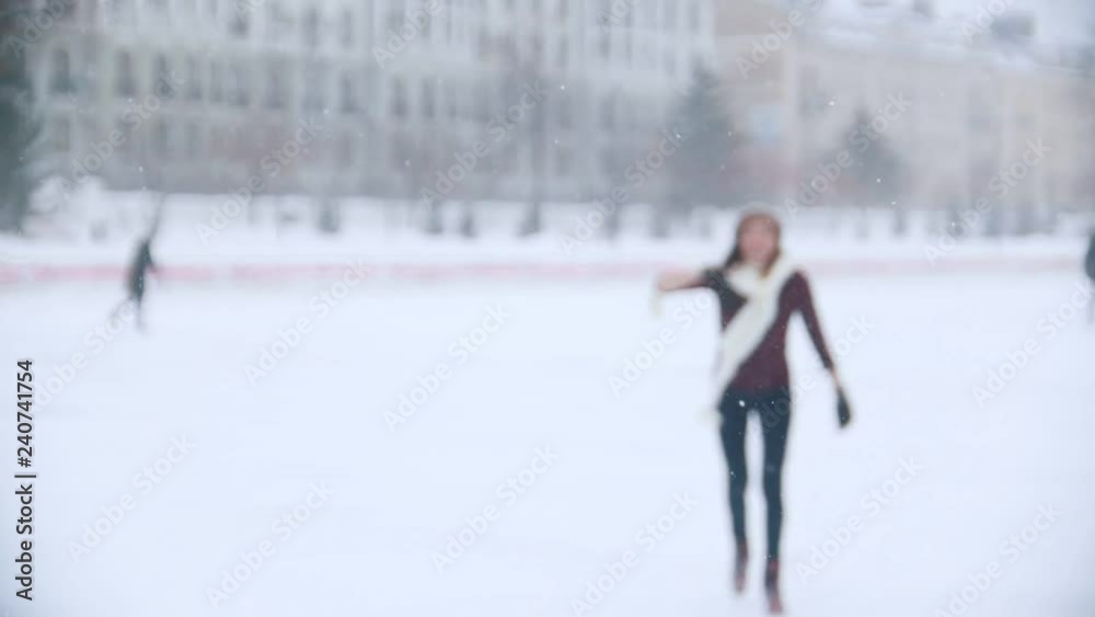 A young woman ice skating outside. Sees her friend, waving to them with a hand, skate closer to the camera. Slow motion A young woman ice skating outside. Sees her friend, waving to them with a hand, skate closer to the camera. Slow motion
