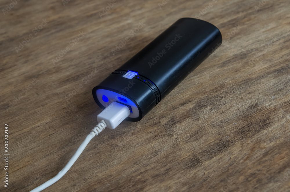 gadget powerbank black on wooden background. portable battery for smartphone. gadget powerbank black on wooden background. portable battery for smartphone.