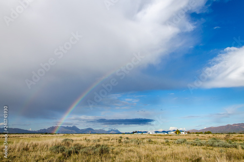 rainbow over field with blue sky and clouds © Chris