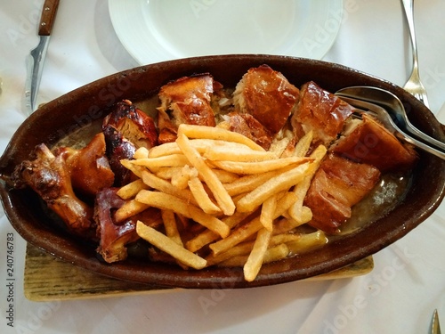 Roast suckling pig (Cochinillo Asado) served with fried potatoes and gravy at a typical Spanish restaurant, Segovia, Spain