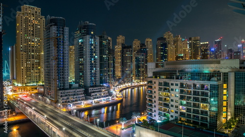 Dubai Marina at night timelapse with light trails of boats on the water and cars, Dubai, UAE
