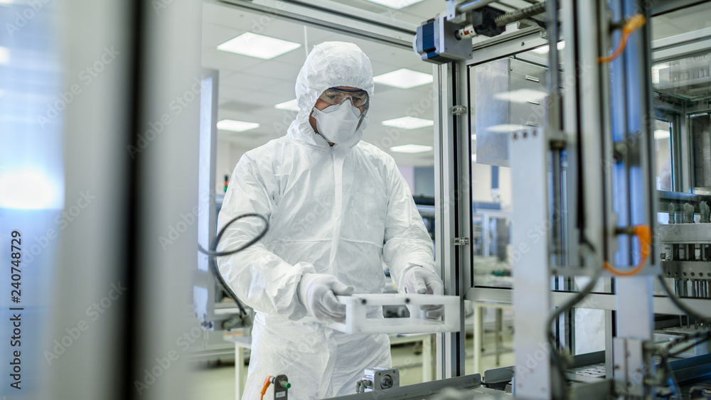 In the Manufacturing Facility Scientist Wearing Sterile Protective Coverall Set's up / Programs Modern Industrial 3D Printer, High Precision Manufacture under Process. Shot from Inside.