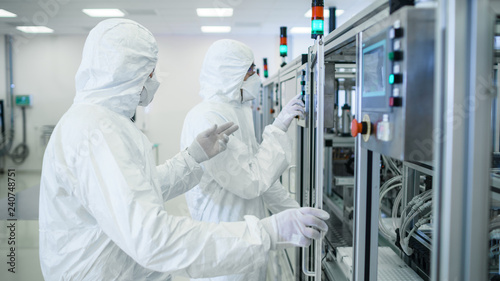 Team of Scientists in Sterile Protective Clothing Work on a Modern Industrial 3D Printing Machinery. Pharmaceutical, Biotechnological and Semiconductor Creating / Manufacturing Process. photo