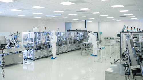 Shot Of Sterile High Precision Manufacturing Laboratory where Scientists in Protective Coverall's Use Computers and Microscopes, doing Pharmaceutics, Biotechnology and Semiconductor Research.