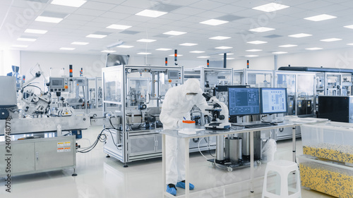 Shot of Sterile Pharmaceutical Manufacturing Laboratory where Scientists in Protective Coverall's Do Research, Quality Control and Work on the Discovery of new Medicine.  photo