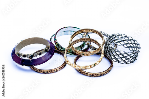 Close up of mixed ornaments or jeweleries to wear them in hands isolated on white which are bangles and some other band like objects.