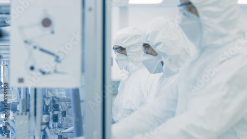 On a Factory Team of Scientists in Sterile Protective Clothing Work on a Modern Industrial 3D Printing Machinery. Pharmaceutical, Biotechnological and Semiconductor Creating / Manufacturing Process.