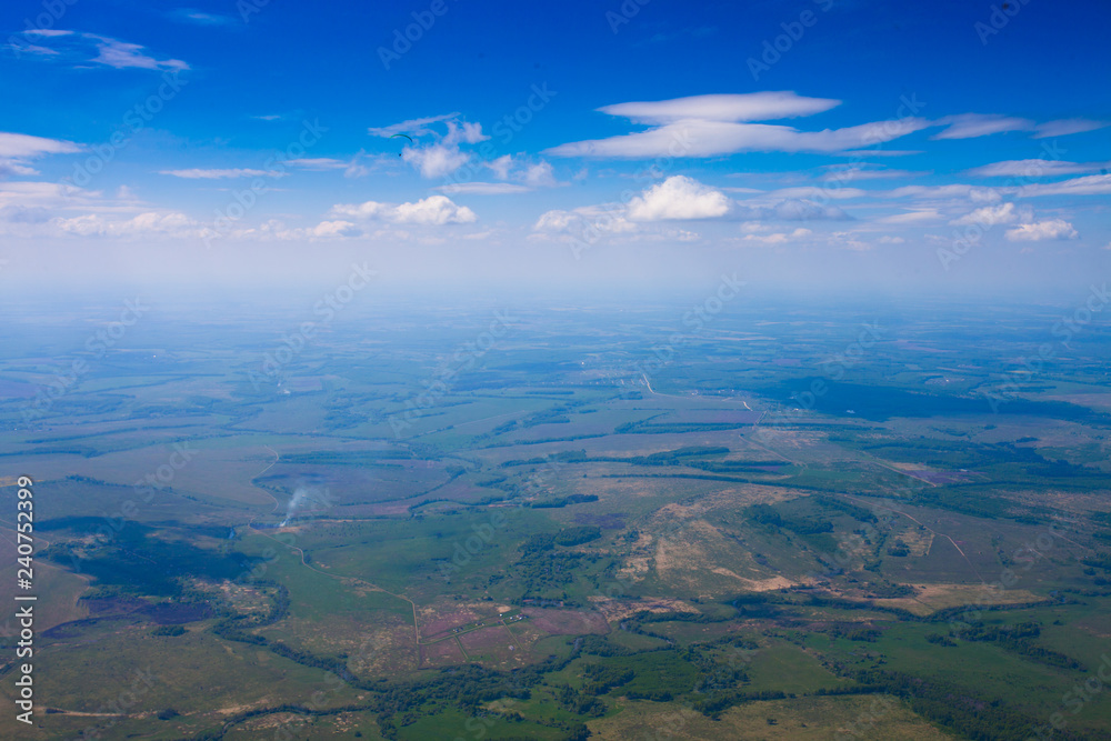 Flight under the clouds above the plain with rivers, fields and forests.