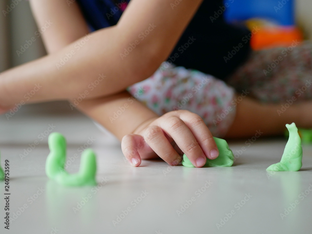 Little baby's hand playing playdough on the house floor - playing dough promotes baby's creativity, imagination, and fine motor skill development Little baby's hand playing playdough on the house floor - playing dough promotes baby's creativity, imagination, and fine motor skill development