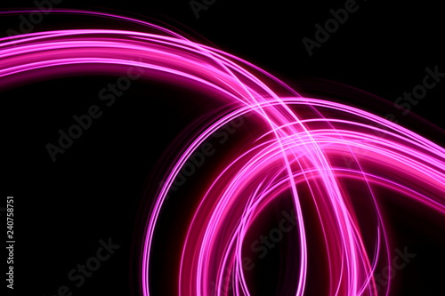 Light painting  long exposure photography  vibrant neon pink swirls of color against a black background