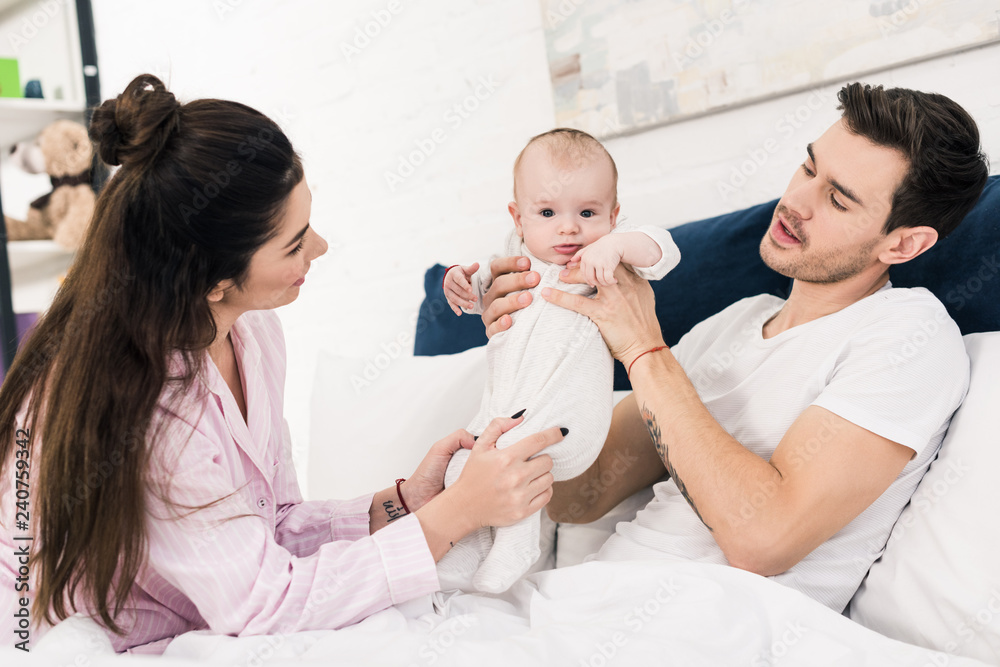 parents and little baby resting on bed together at home parents and little baby resting on bed together at home