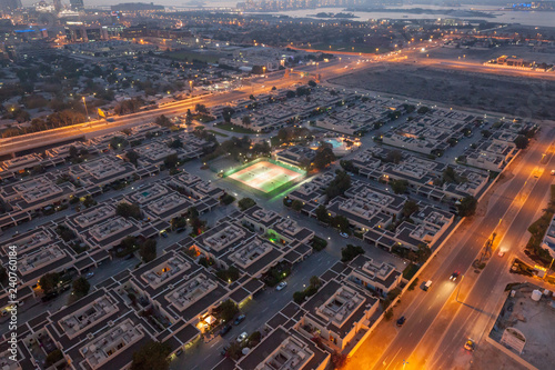 Illuminated tennis courts at Palma Spring Village, Dubai, UAE, in early evening