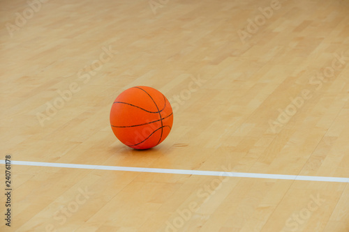Basketball on a hardwood court floor as a sports and fitness symbol of a team leisure activity playing with a leather ball dribbling and passing in competition tournaments.