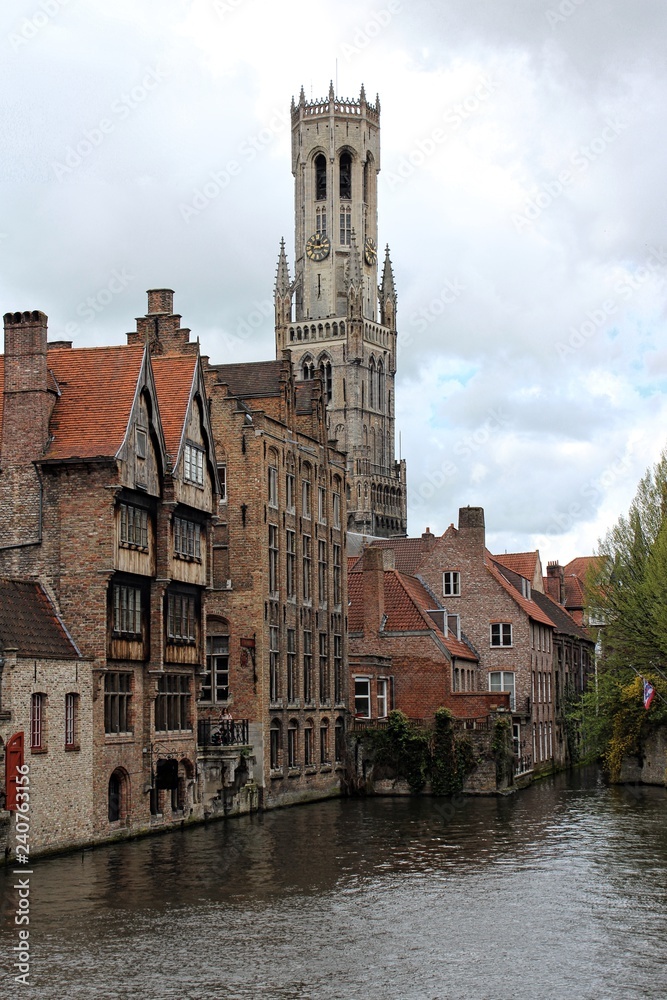 Bruges, Belgium. Scenery with water canal and view of Belfry Tower.