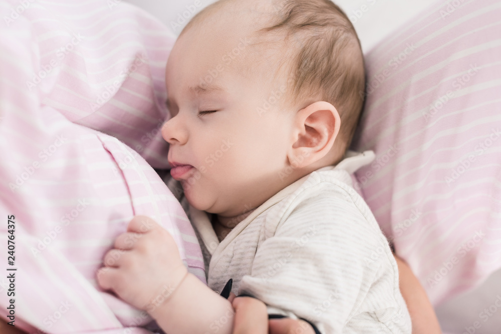 partial view of cute baby sleeping on mothers hands partial view of cute baby sleeping on mothers hands
