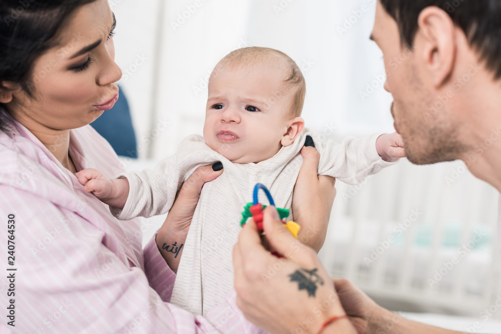parents looking at emotional baby in hands at home parents looking at emotional baby in hands at home