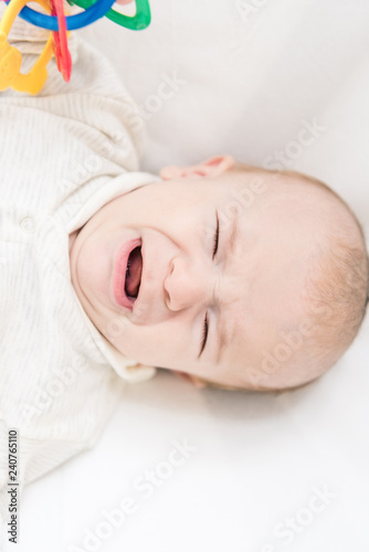 overhead view of little crying baby with toy