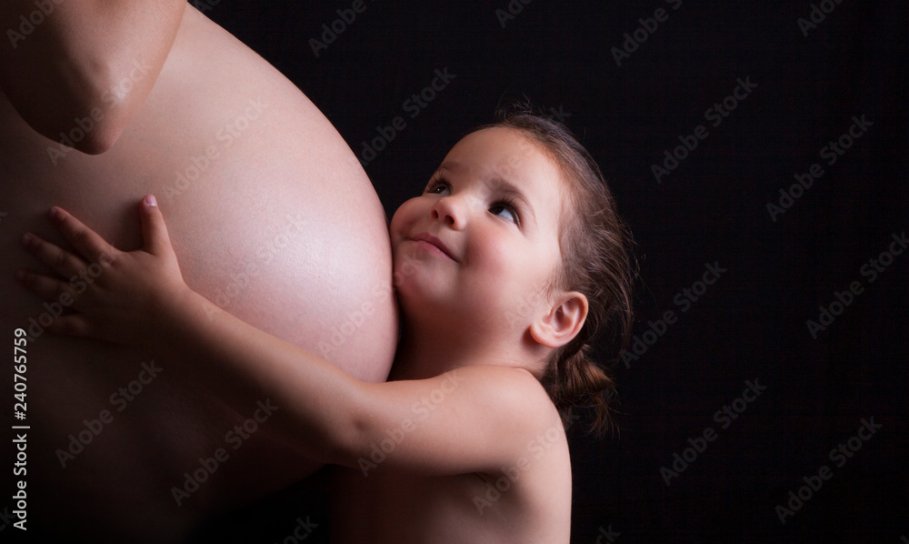 Naklejka premium Young attractive mother with her toddler daughter. Seventh month of pregnancy