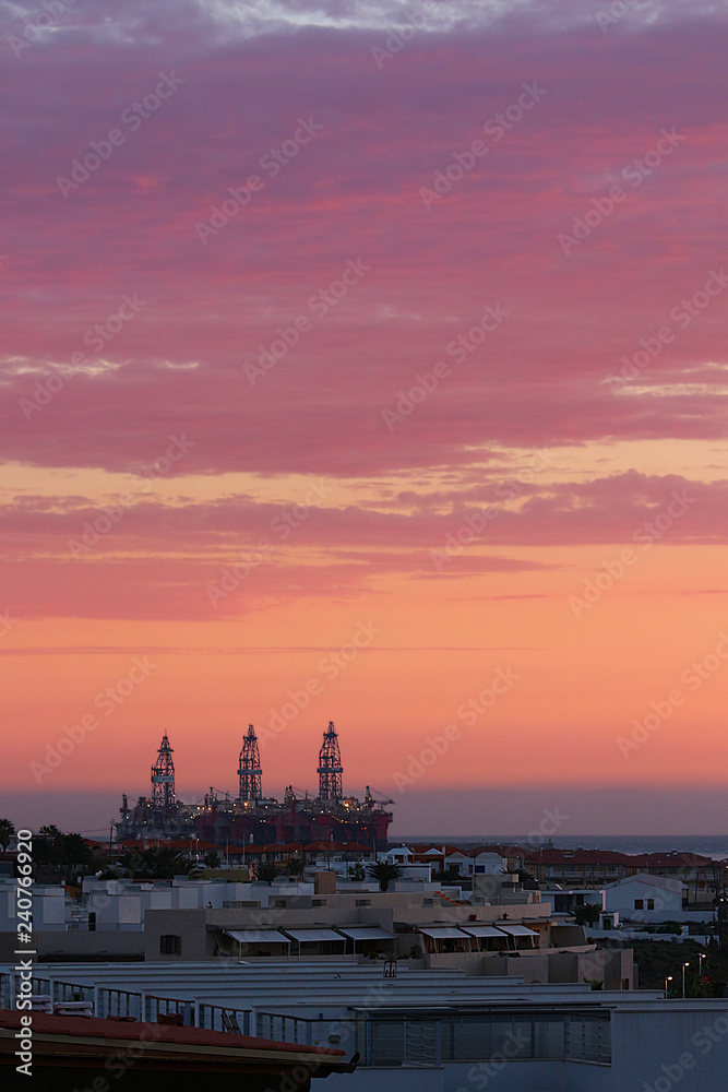 Obraz premium Sunrise over oil drilling rigs in port near dwelling, El Medano, Tenerife