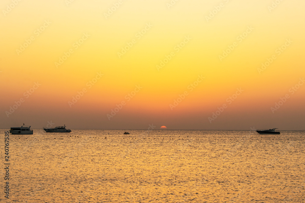 boat silhouetts on the shores of the red sea at sunset in Makadi Bay Egypt golden colors