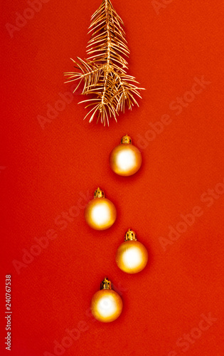 Multiple Christmas gold baubles and single pine tree branch creative decoration pattern on the red background