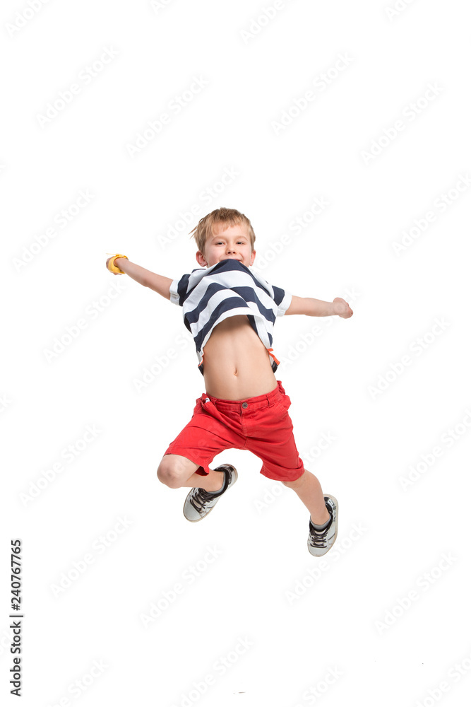 Adorable blond boy jumping and raises his hands up. Isolated on white background. Shooting in the studio