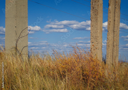Concrete pillars. Yellow grass. Blue sky. Steppe. Abstract landscape