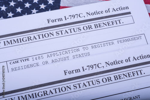Two Form I - 797C Application to extend change nonimmigrant status (Notice of action, I539, immigration status) on flag of USA background. Diagonal view.